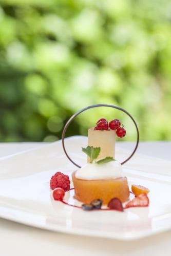 a piece of cake on a white plate with fruit at Hotel Löwenhof in Bressanone