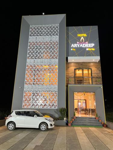 Un coche blanco aparcado delante de un edificio en Hotel Aryadeep, en Phardāpur