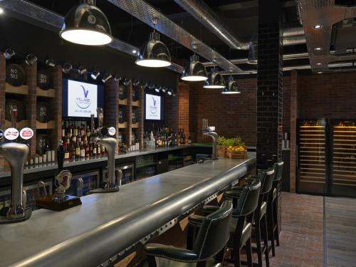 a bar with chairs and a counter with alcohol at Village Hotel Edinburgh in Edinburgh
