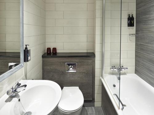 a bathroom with a toilet and a sink and a tub at Village Hotel Edinburgh in Edinburgh