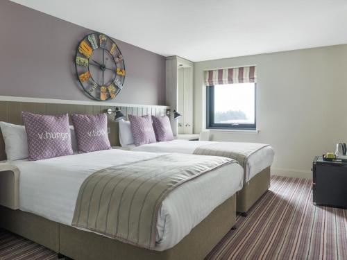 Dos camas en una habitación de hotel con un reloj en la pared en Village Hotel Edinburgh, en Edimburgo