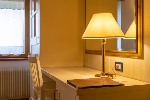 a lamp sitting on a desk with a mirror at Hotel Calvi-Ristorante Mainor in Vittorio Veneto