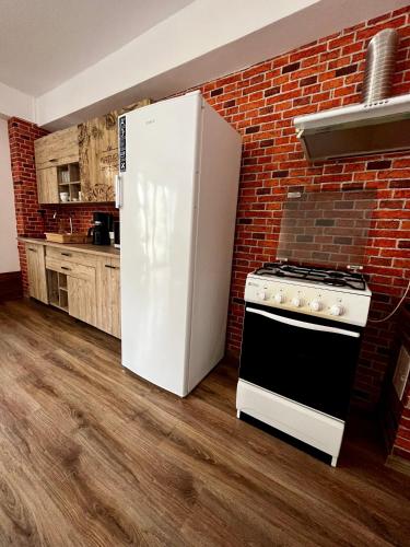 a kitchen with a white refrigerator and a brick wall at Vila SOFIA in Haţeg