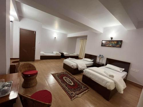 ein Hotelzimmer mit 2 Betten, einem Tisch und Stühlen in der Unterkunft The Sherpa's Abode in Gangtok