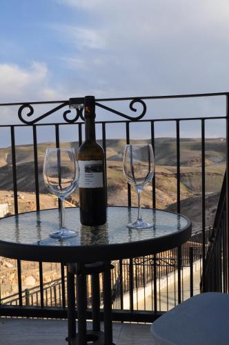 a bottle of wine and two wine glasses on a table at Vastu Dead Sea apartment in Arad