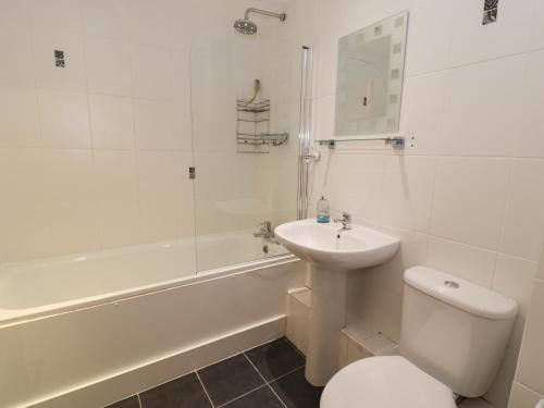a white bathroom with a toilet and a sink at Whistle Stop Apartment in Porthmadog