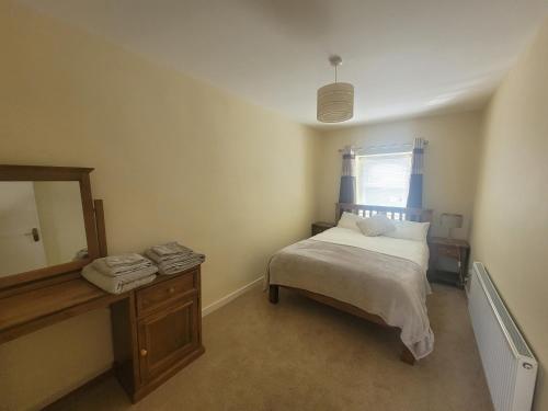 a small bedroom with a bed and a mirror at Stoneyford Village in Stonyford