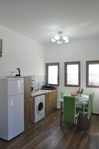 een keuken met een tafel en groene stoelen en een keuken met een wasmachine bij Vastu Dead Sea apartment in Arad