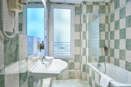 La salle de bains est pourvue d'un lavabo, d'une baignoire et d'une fenêtre. dans l'établissement Hôtel Kabanel by Happyculture, à Paris