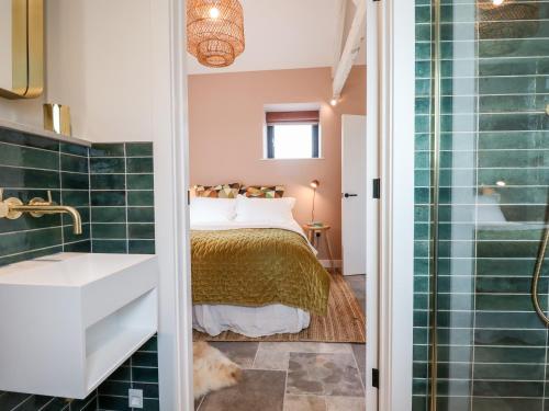 a bathroom with a bed and a shower and a sink at 1 Caddaford Barns in Buckfastleigh