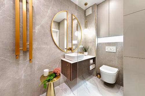 La salle de bains est pourvue d'un lavabo et d'un miroir. dans l'établissement Wyjątkowy Taupe Apartament w centrum Łodzi, à Łódź