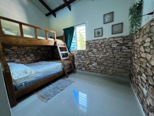 a bedroom with two bunk beds and a stone wall at Villa La Grande in Jarabacoa