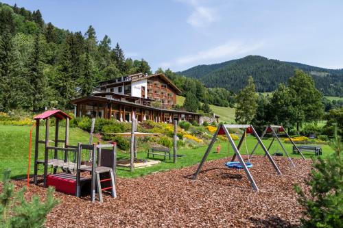 a playground in front of a house with a building at Hotel OTP Birkenhof in Bad Kleinkirchheim