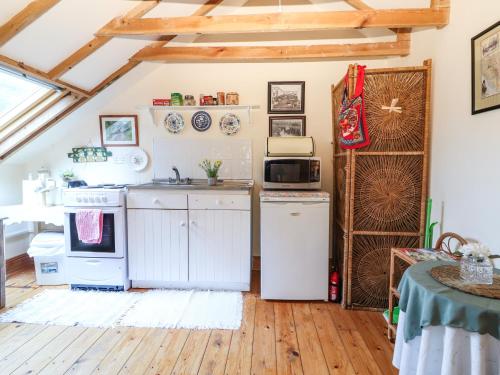a kitchen with white appliances and a wooden floor at Mrs Delaney's Loft in Ardfinnan
