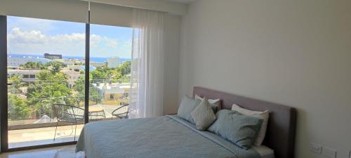 a bedroom with a bed and a large window at Menesse mitdtown2 , AVE 25TH in Playa del Carmen