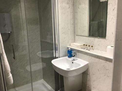 La salle de bains blanche est pourvue d'un lavabo et d'une douche. dans l'établissement Belvedere Guest House, à Stonehaven