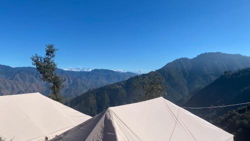 two white tents with mountains in the background at Ananta Prana in Mussoorie