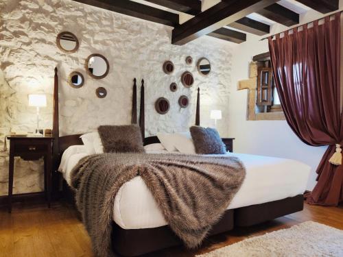 a bedroom with a bed and a wall with rocks at Hotel Casa del Marqués in Santillana del Mar