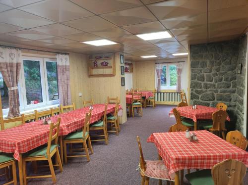 a dining room with tables and chairs and a stone wall at Chata Zahradky in Belá