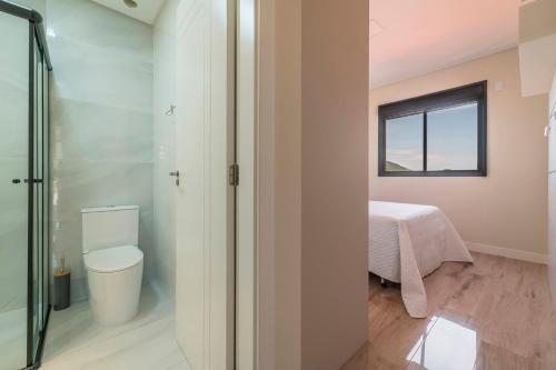a bathroom with a toilet and a bed in a room at Apartamento 2 suítes em Bombas in Bombinhas