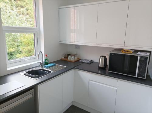 a kitchen with white cabinets and a microwave and a sink at Victorian Renovation Room 3 in Liverpool