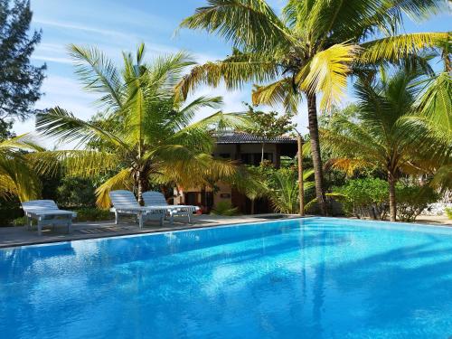 una piscina con 2 sillas y palmeras en Tropical Garden, en Tangalle