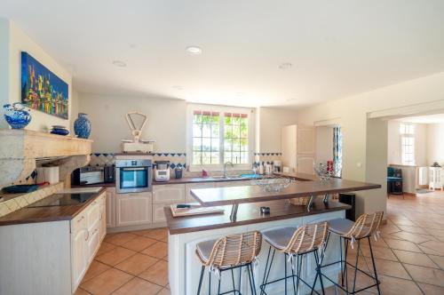 - une grande cuisine avec un comptoir et des tabourets dans l'établissement Chez Annie et William, à Montpouillan