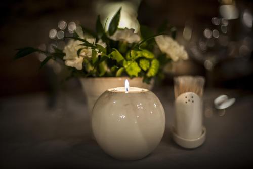 a white candle and a vase with flowers on a table at Piwnica Rycerska Kęty in Kęty