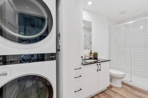 a white bathroom with a washing machine and a toilet at Initial / New Yorker / Centre-ville de Québec in Quebec City
