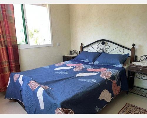 a bedroom with a bed with a blue comforter at Superbe appartement avec piscine in Mohammedia
