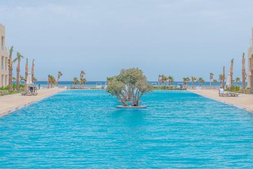 uma piscina com uma árvore no meio da água em Mangroovy Seaview 3BR Beach and Pool Free access em Hurghada