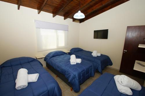 Habitación con 3 camas azules y TV. en Complejo de cabañas Atrapasueños en El Calafate