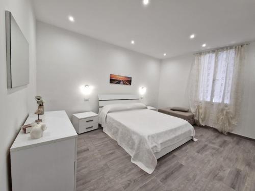 a white bedroom with a bed and two tables at La casa di Teresa in Taranto