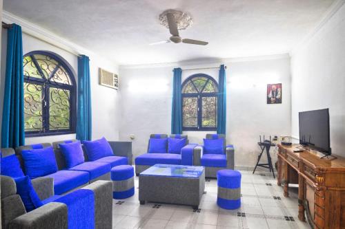 a living room with blue couches and a tv at Hilltop 4BHK Villa with Private Pool Near Candolim in Old Goa