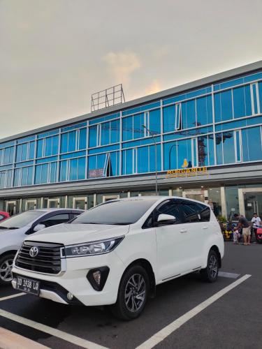 a white car parked in a parking lot in front of a building at Rental Mobil Makassar in Makassar