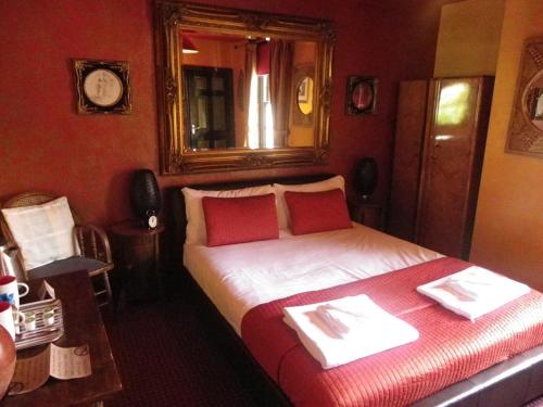 um quarto com uma cama com paredes vermelhas e um espelho em Fifteens of Swinley em Wigan