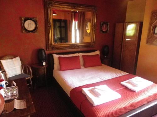 een slaapkamer met een bed met rode muren en een spiegel bij Fifteens of Swinley in Wigan