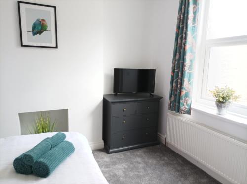 a bedroom with a bed with a television and a dresser at Victorian Renovation Room 4 in Liverpool