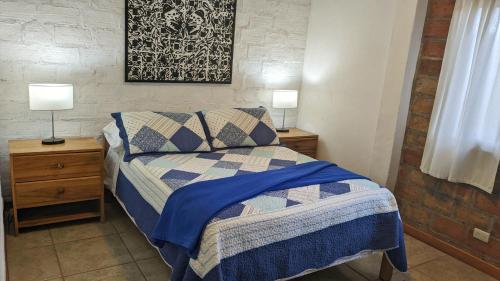 a bedroom with a bed and two night stands with lamps at Alpha House in Vilcabamba