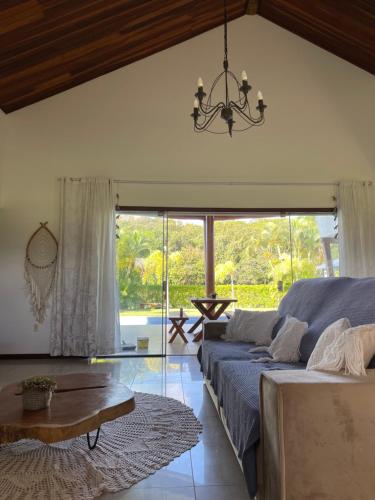 a living room with a bed and a chandelier at Casa Asa Delta - Pipa Natureza in Pipa