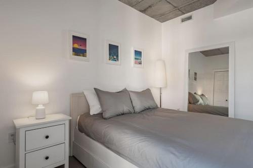 ein weißes Schlafzimmer mit einem Bett und einem Spiegel in der Unterkunft Initial / Espace M / Centre-ville de Québec in Québec