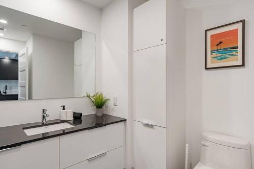 ein weißes Badezimmer mit einem Waschbecken und einem Spiegel in der Unterkunft Initial / Espace M / Centre-ville de Québec in Québec