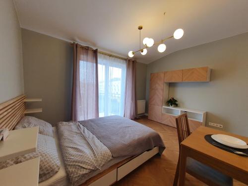 1 dormitorio con cama, mesa y ventana en Apartament Imara-klimatyzacja, miejsce parkingowe, en Łódź