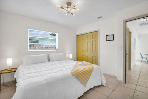 a white bedroom with a white bed and a yellow door at LoKal Rental Tropical Florida destination in Fort Lauderdale