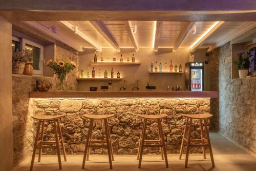 a bar with wooden stools and a stone wall at Sea Wind Villas and Suites in Tourlos