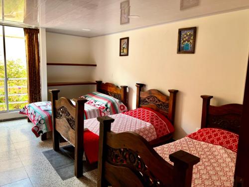 a bedroom with three beds and a window at Hospedaje Lycaste in Tibasosa