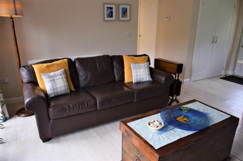 a brown leather couch in a living room with a table at Ridge View Lodge in Dumfries