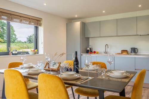 a dining room with a table and yellow chairs at 1 Long Barn in Sotherton