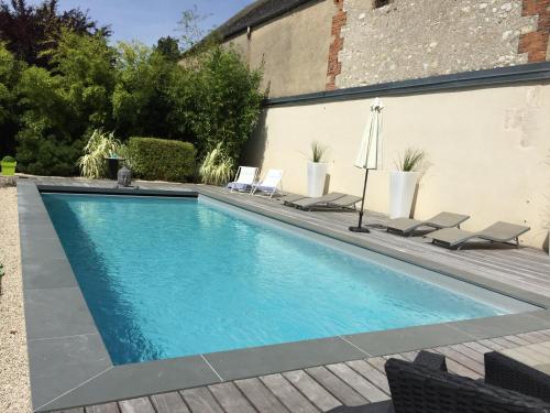a swimming pool with two chairs and an umbrella at VILLA MARLISE Chambre Hôtes in Saint-Satur