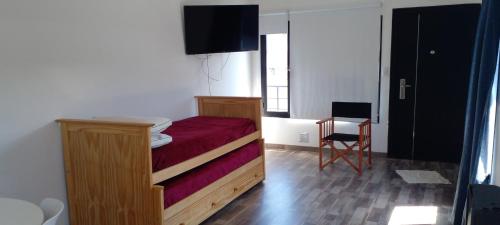 a small bedroom with a bed and a chair at La Pancora in Esquel